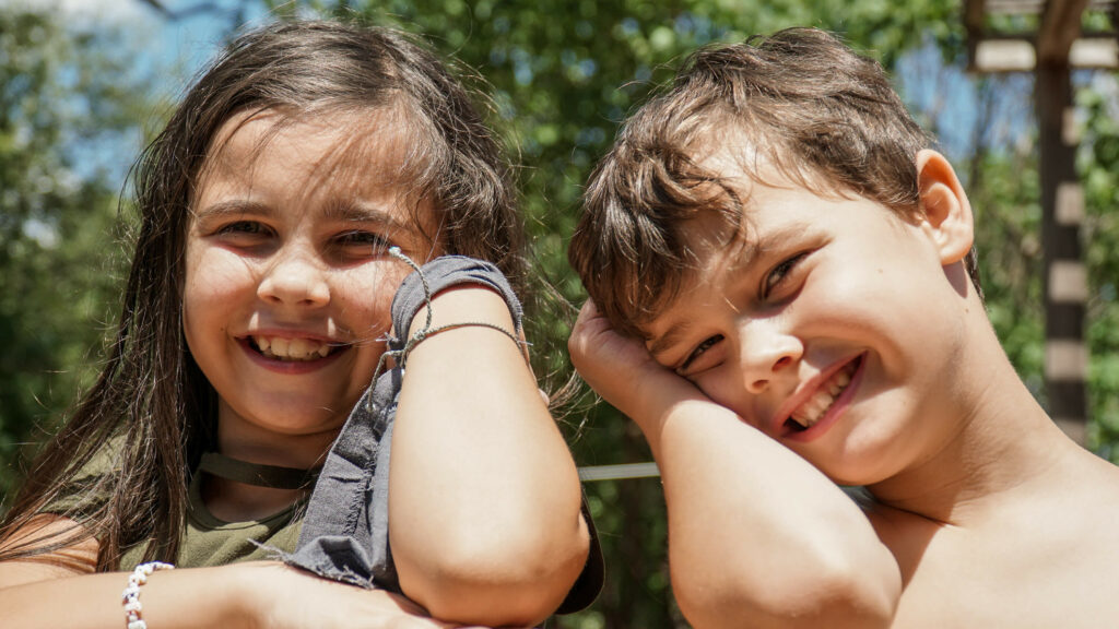 Photograph of two happy children smiling to camera.