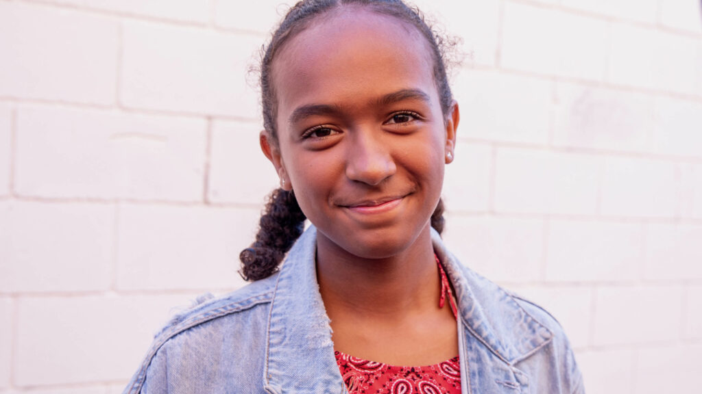 Close up photograph of young girl smiling to camera.