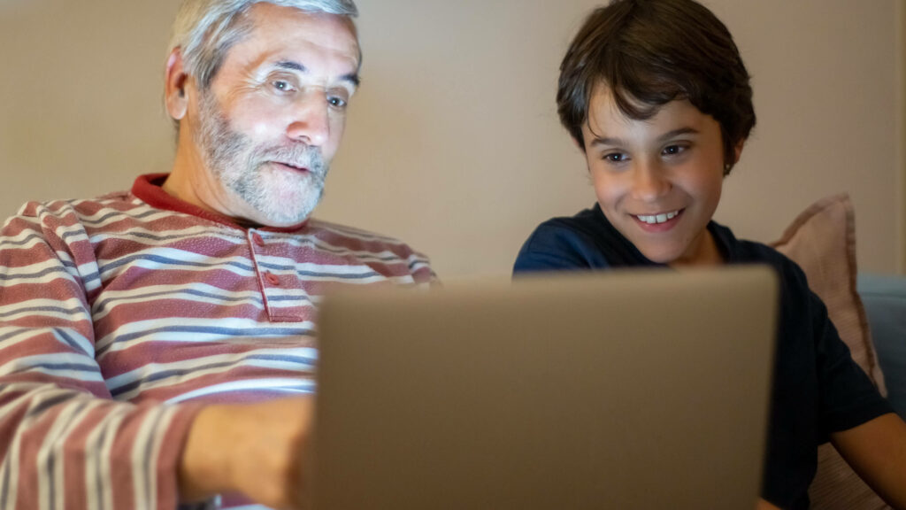 Older man and young boy looking at laptop together.