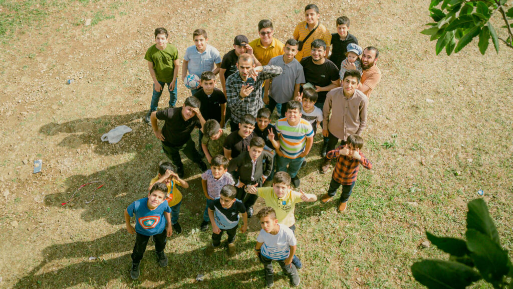 Group photograph of people looking up to camera standing on grass.