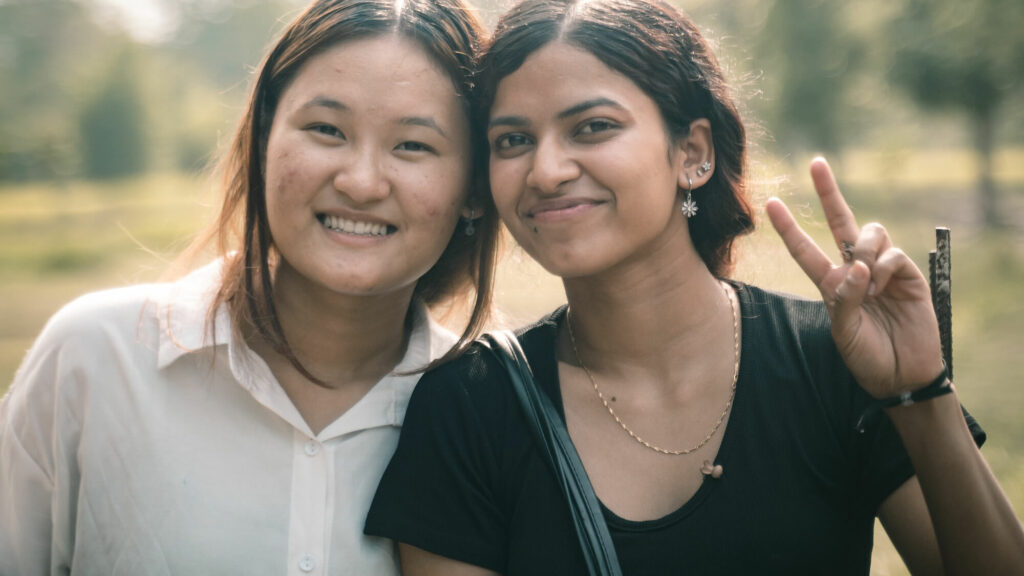 Two happy women, outdoors, looking to camera.