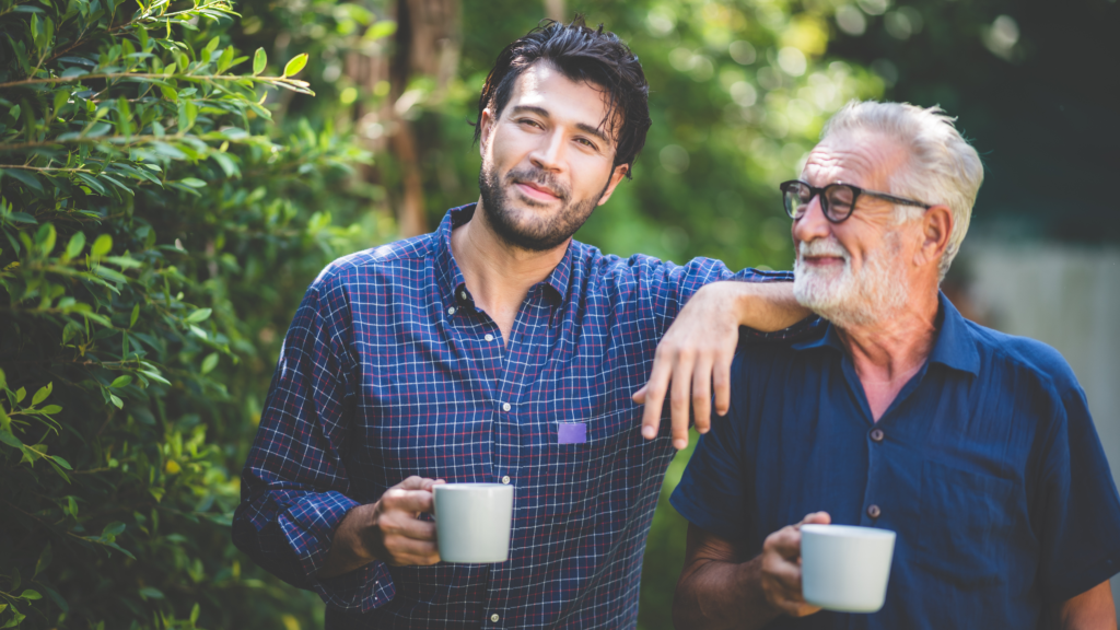 Retired father and son in late twenties spending time together in the garden with a cup of tea.